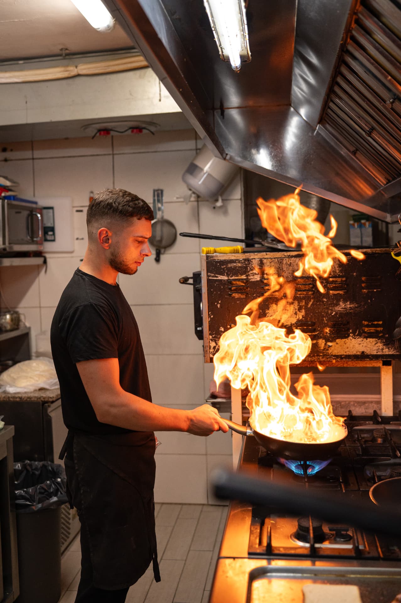 A cook flambéing a pan in the small Bon Appetit kitchen