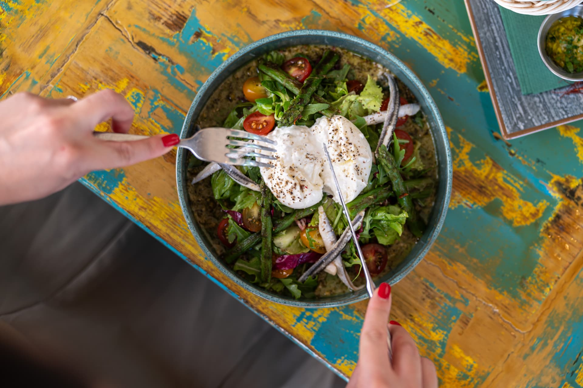 Burrata salad with cherry tomatoes, asparagus and anchovies on a hand-painted table