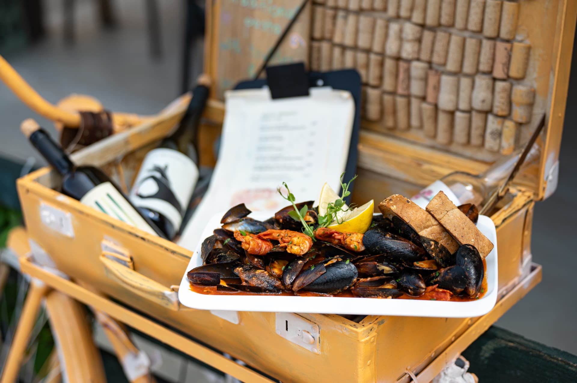 Mussels and shrimps in red buzara sauce served on a white plate with bread and lemon